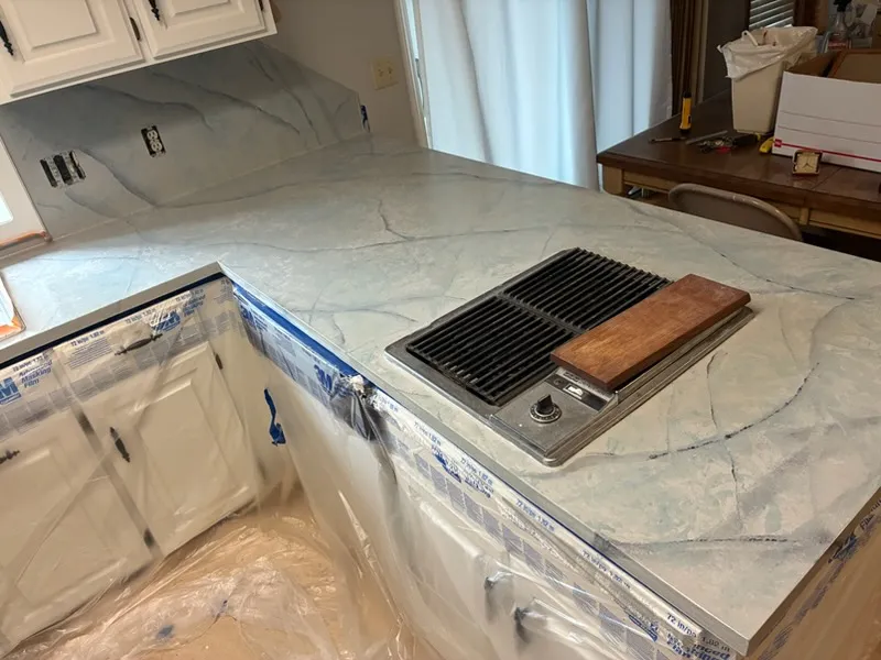 Kitchen peninsula with a marble-look countertop around a built-in cooktop