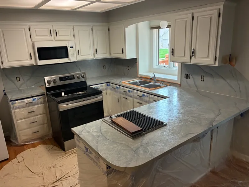 Kitchen with gray-blue marble-look countertops, a backsplash to match, and white cabinets
