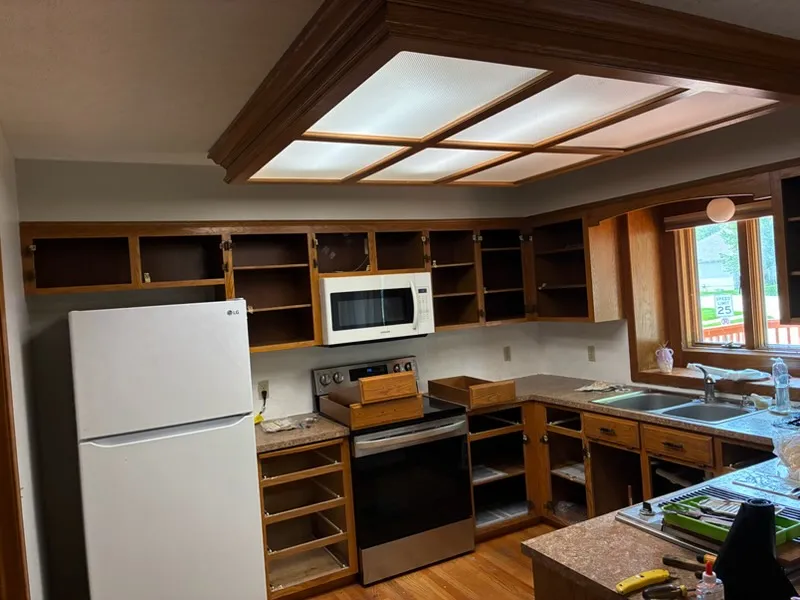 Kitchen before: speckled brown countertops and wood cabinets with the doors off